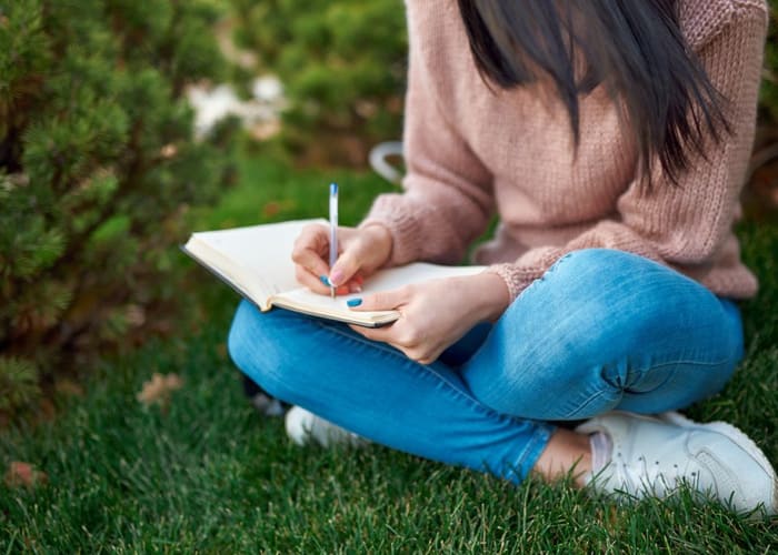 female-college-student-writing-in-journal-outside