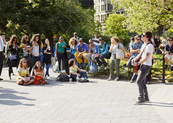 male street performer with guitar brining crowd together in city