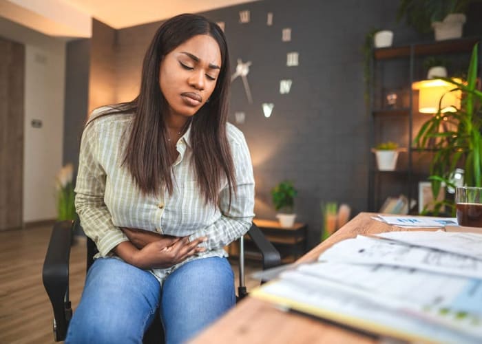 college-student-studying-at-home-and-holding-stomach-from-depression-making-her-ill